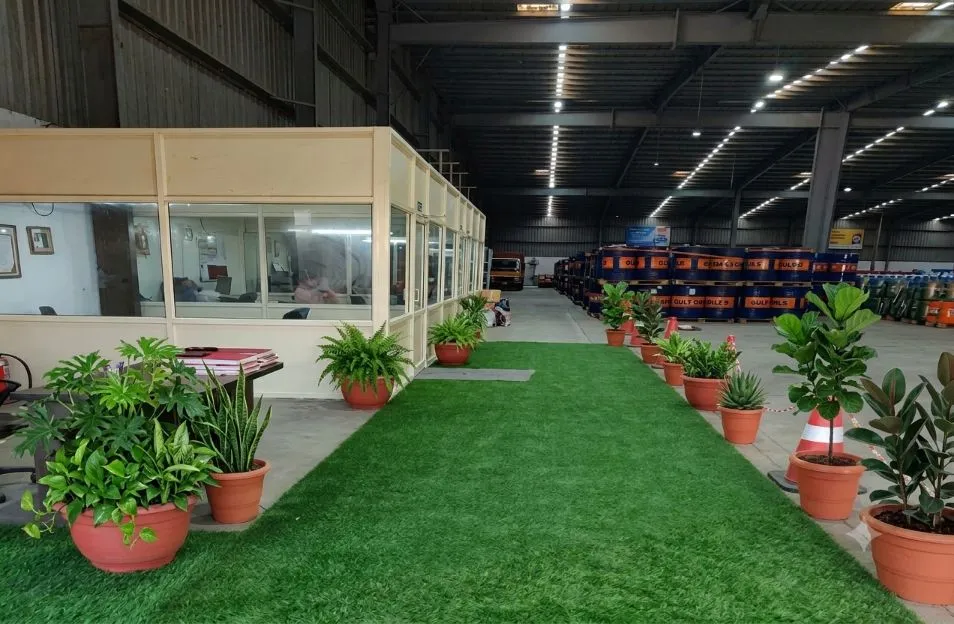 Warehouse office cabin with plants, and drums stacked behind